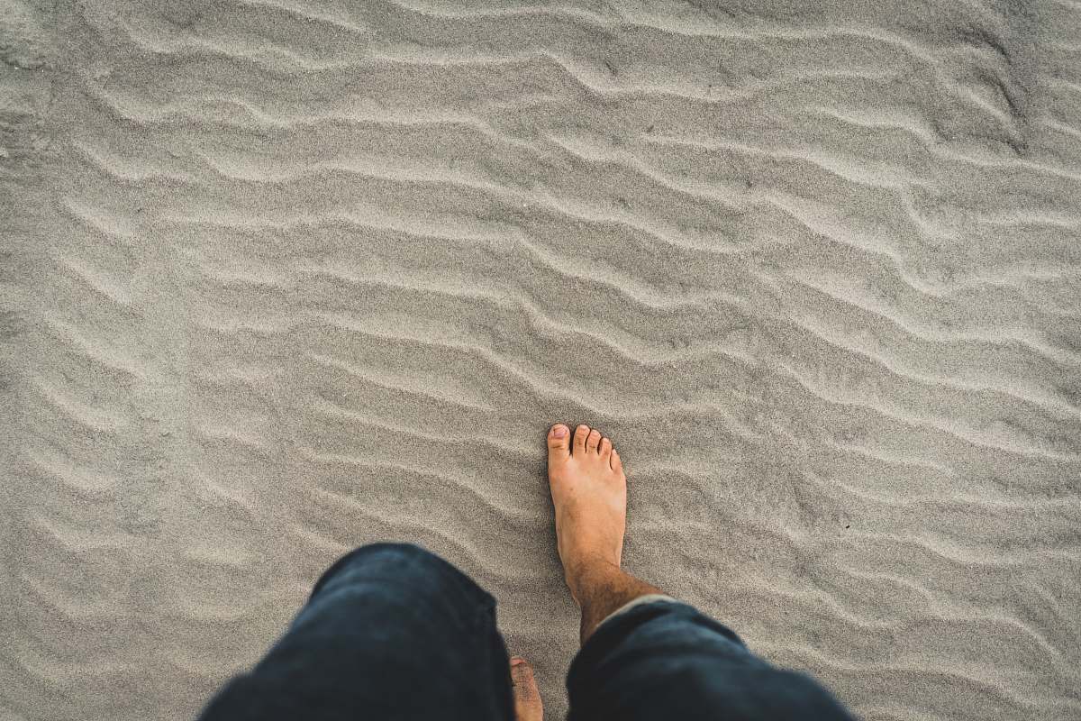 outdoors man in blue denim jeans walking through the sand kiawah island
