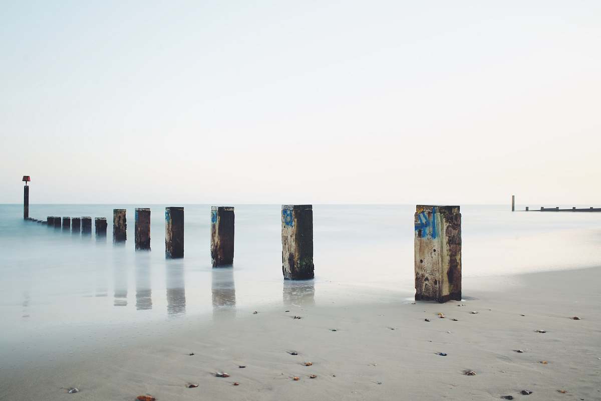 water gray concrete post on seashore under gray sky ocean