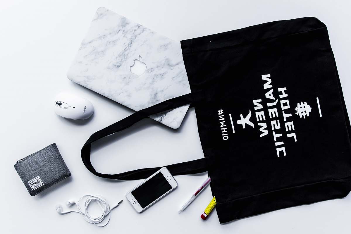 branding flat lay photography of tote bag beside iPhone and wallet gear