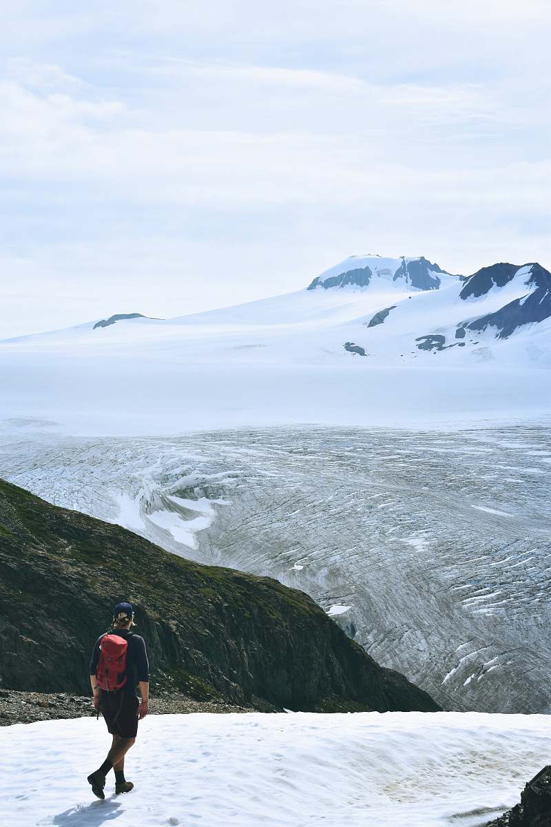 person man walking on snow facing mountain mountain