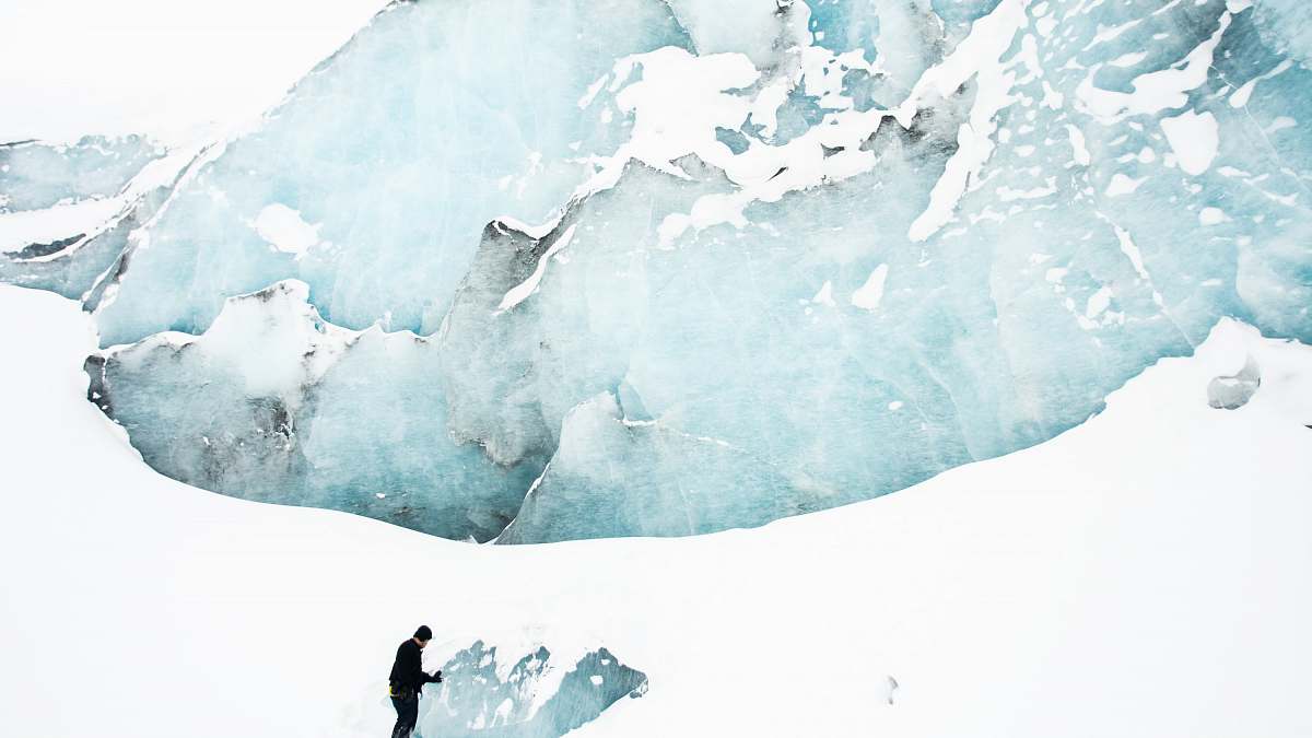glacier person standing on snow field near mountain ice
