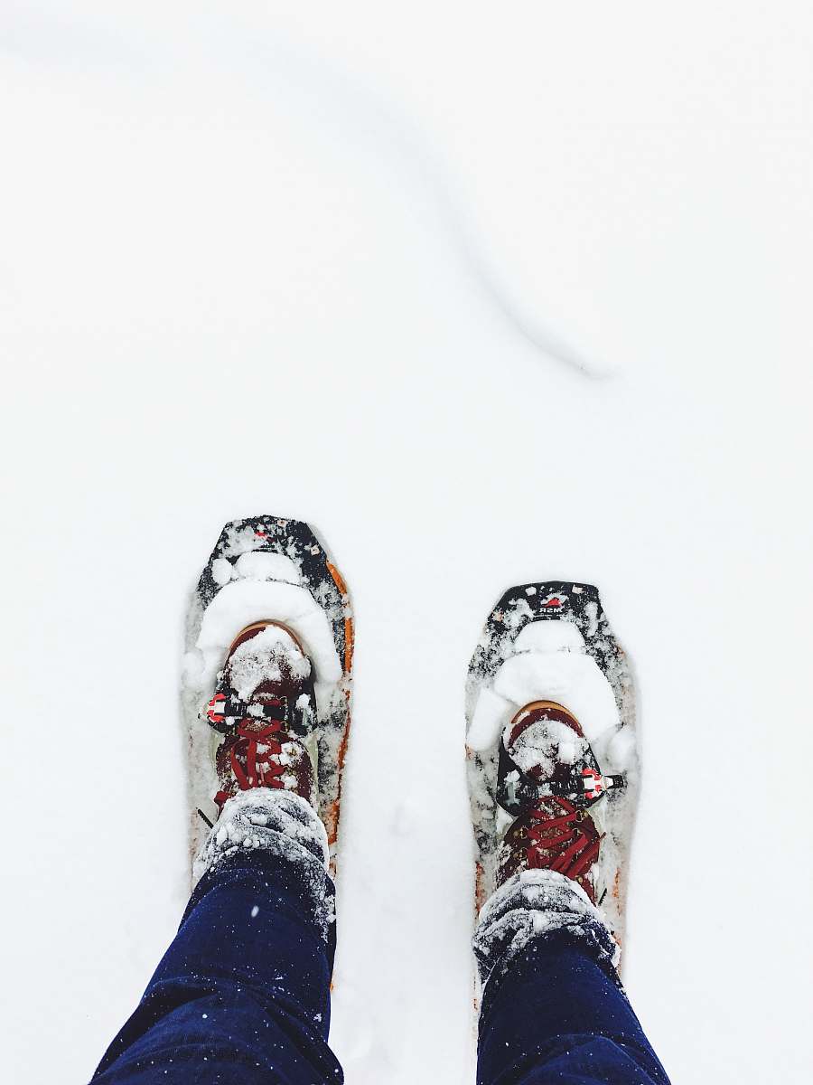 winter person wearing blue jeans standing on snow shoe