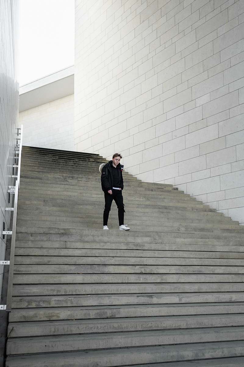 handrail man walking near stairway during daytime banister