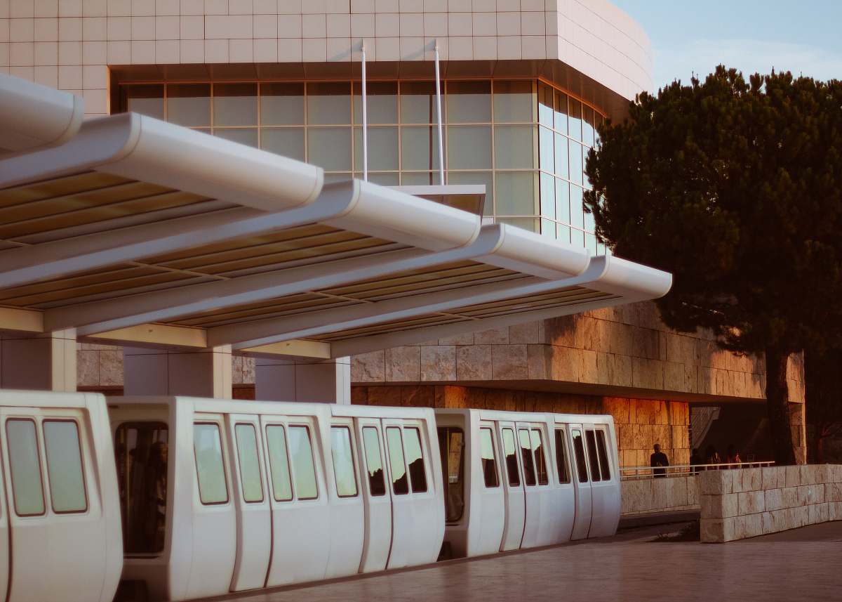 train brown and white concrete building beside tree under blue sky at daytime transportation