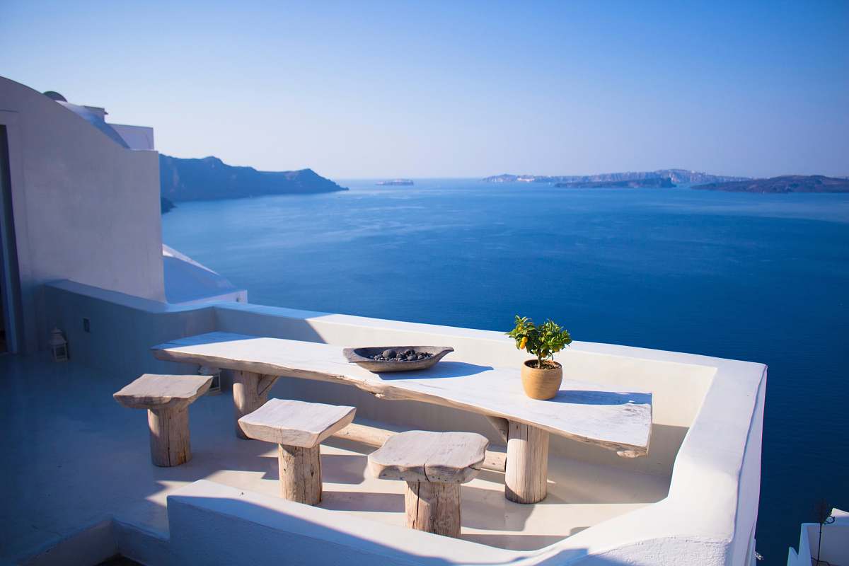 greece bench and dining table near body of water under calm sky hotel