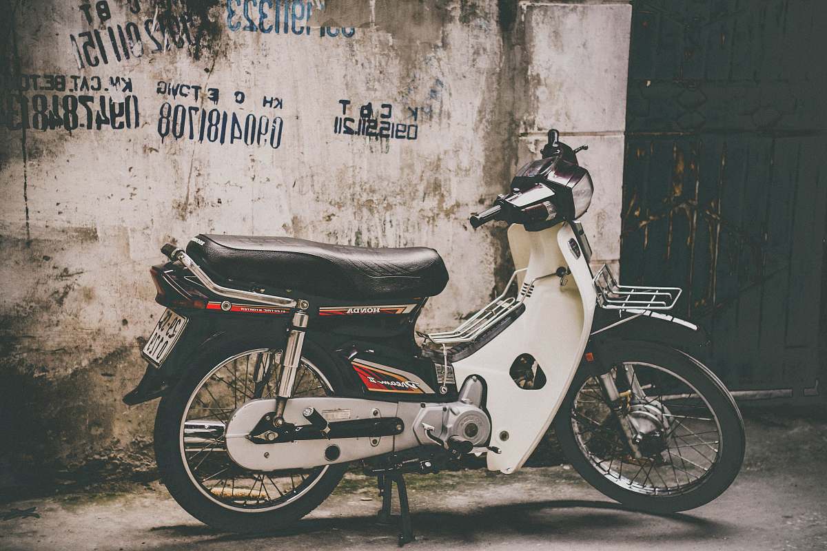 motorcycle white and black underbone motorcycle parked near the wall vehicle