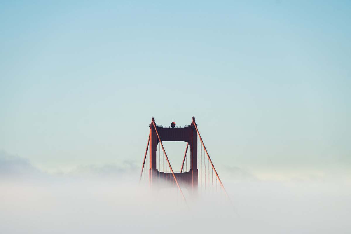 city red concrete bridge surrounded by clouds bridge