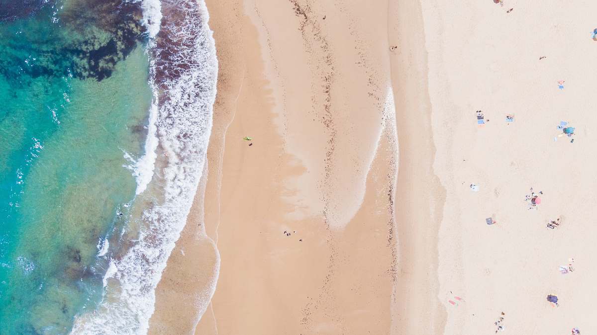 ocean aerial photo of people on brown sand near body of water sea
