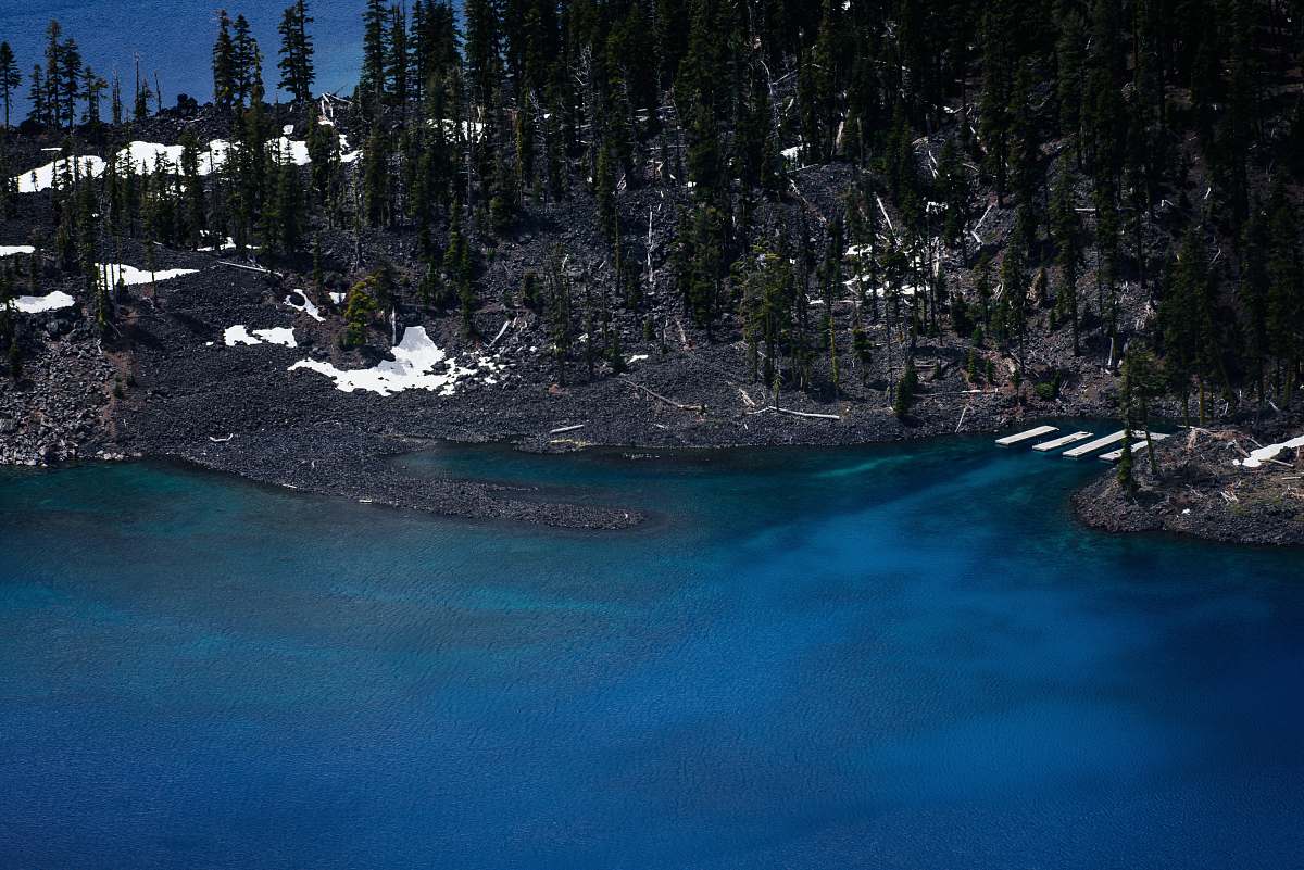lake black sand beach with green trees near at body of water forest