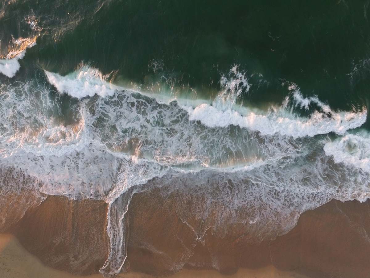 sea body of water splashing on a sand ocean