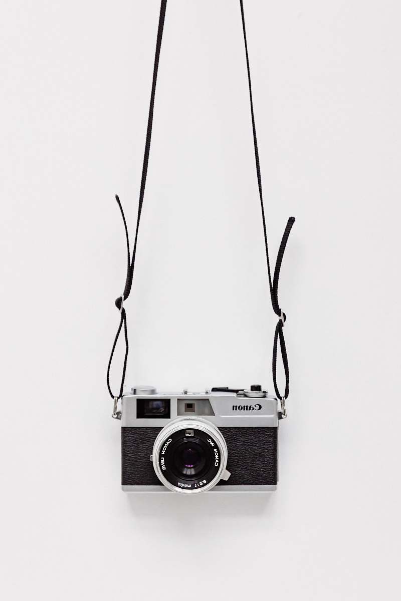 black-and-white black and gray Canon camera on white surface camera