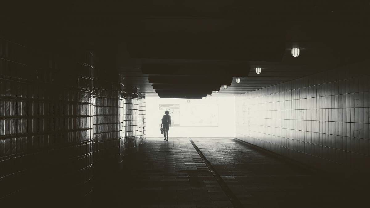 corridor gray scale photography of person walking in bridge light