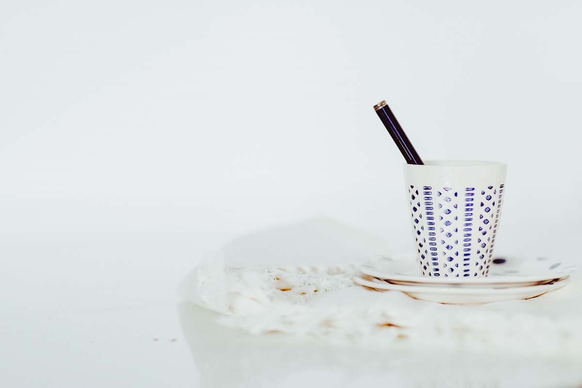 minimal white cup with pen on white panel coffee