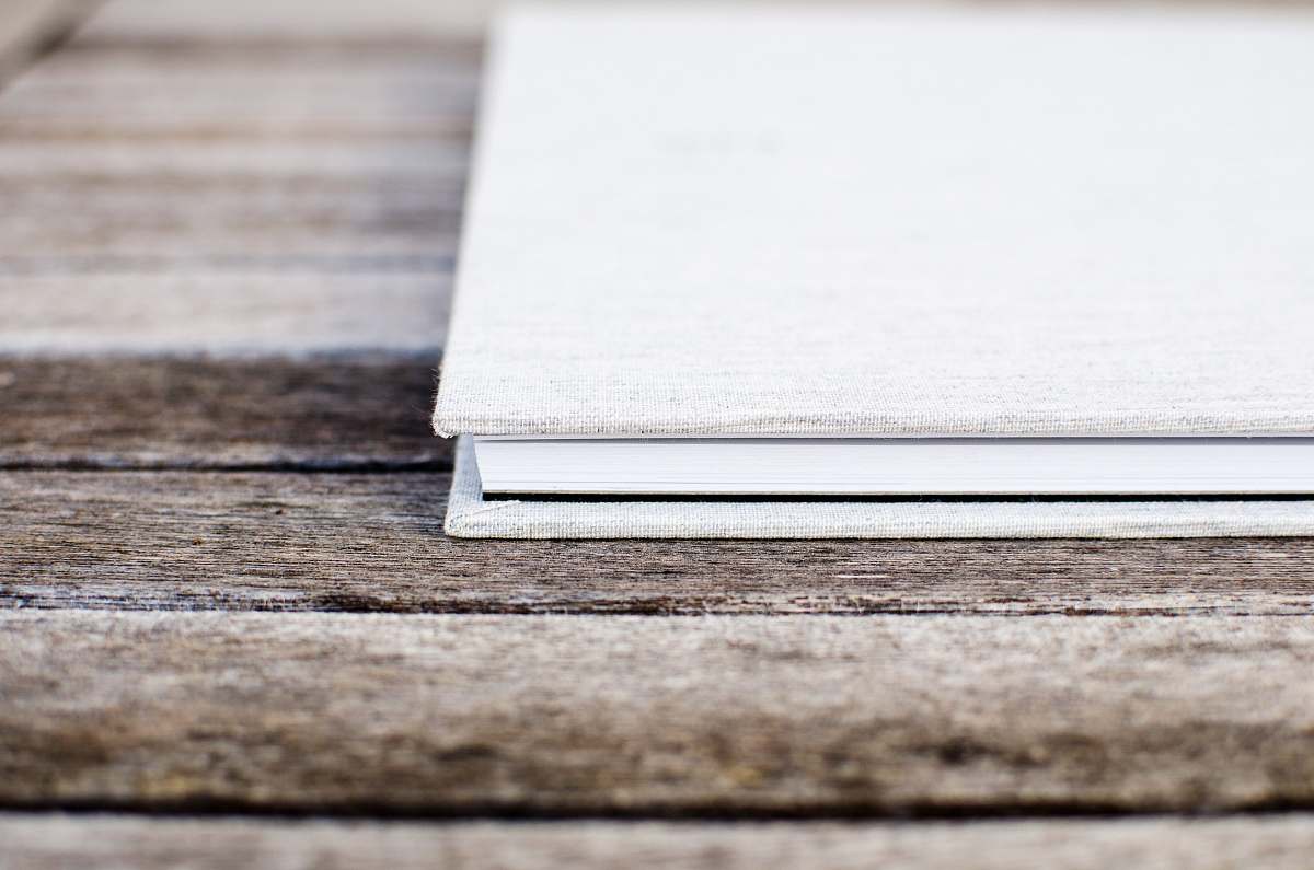 book White hardcover book sitting on the wooden table wood