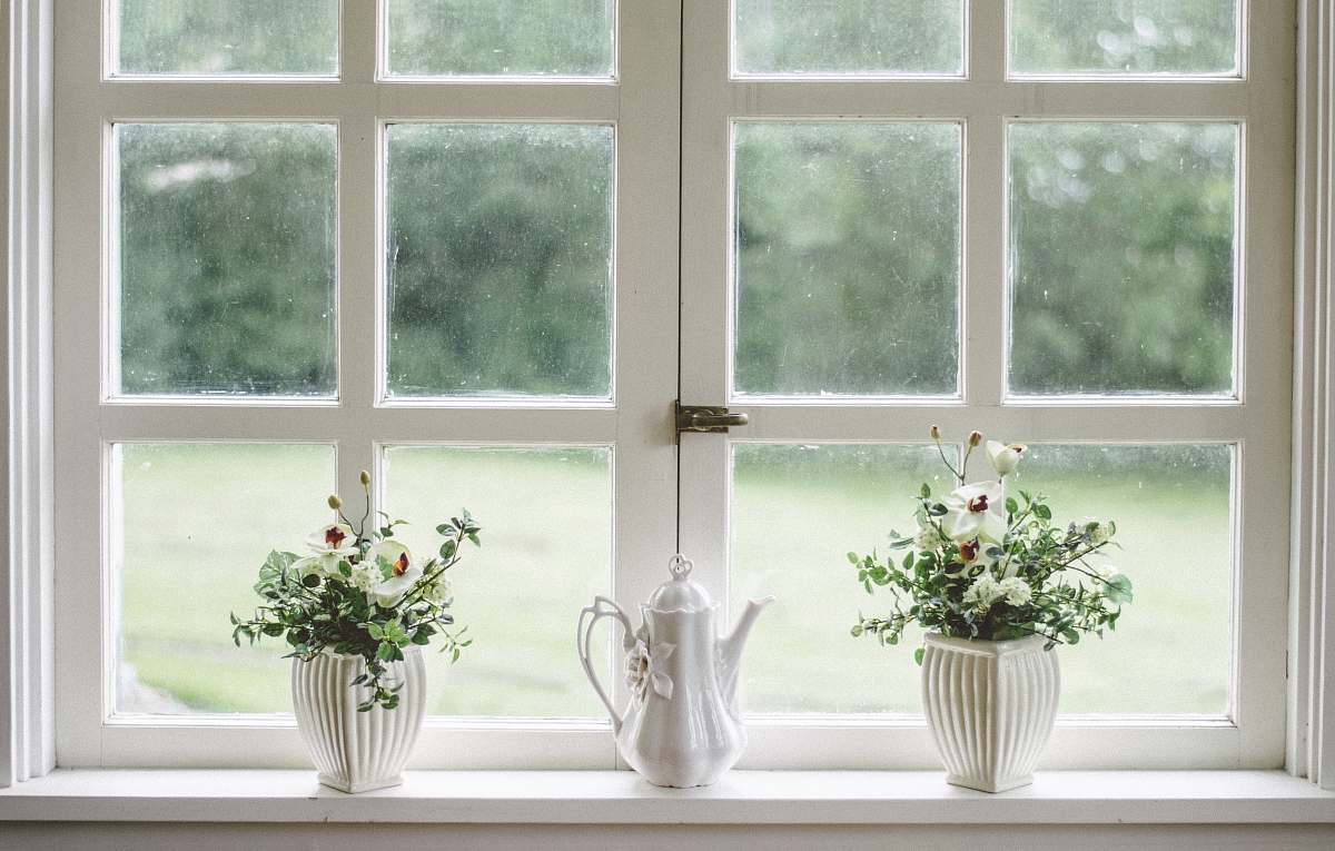 interior white teapot and tow flower vases on windowpane window