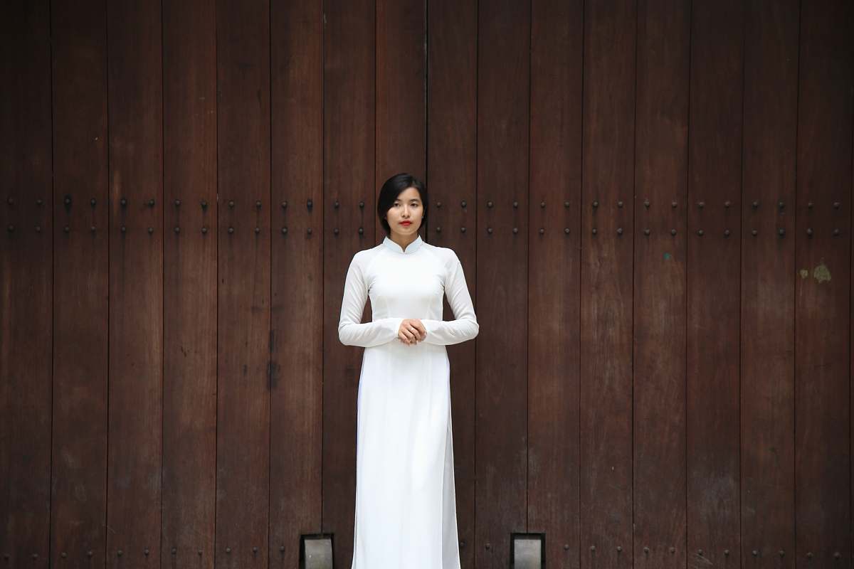 dress woman standing near brown wall person
