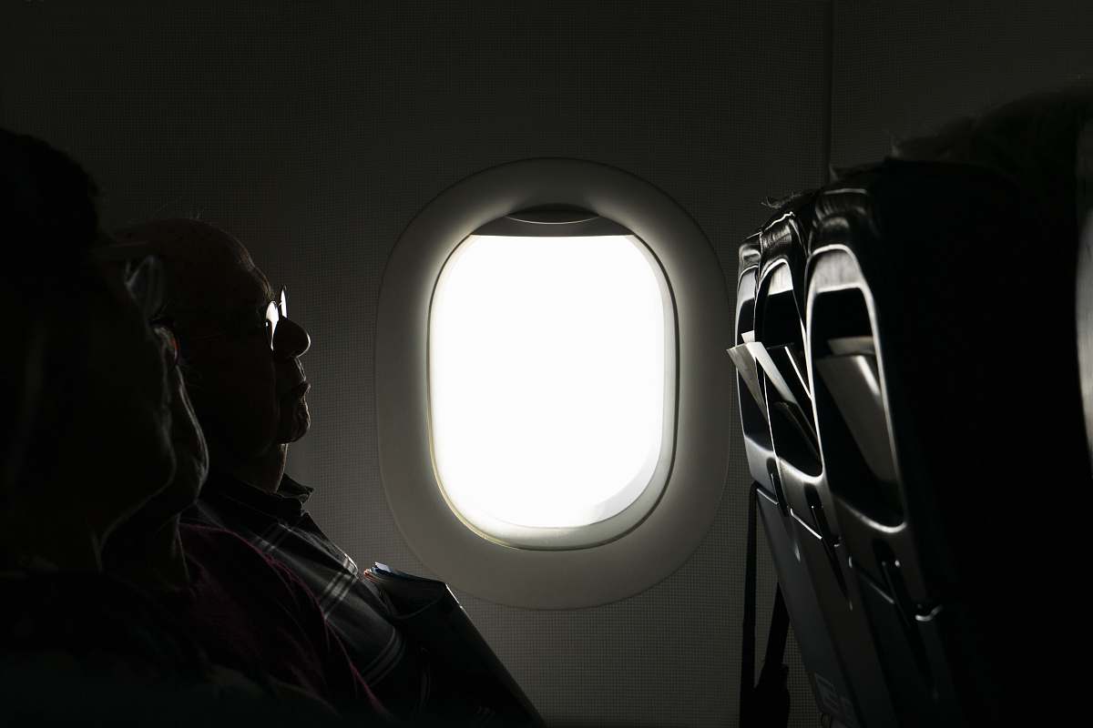 porthole two person sitting inside of airplane passenger