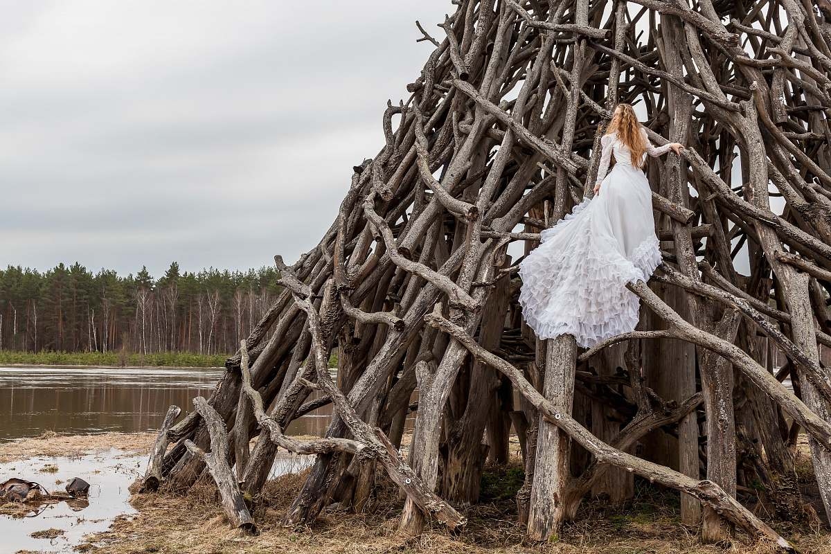 wood woman in white dress on piled wood logs river