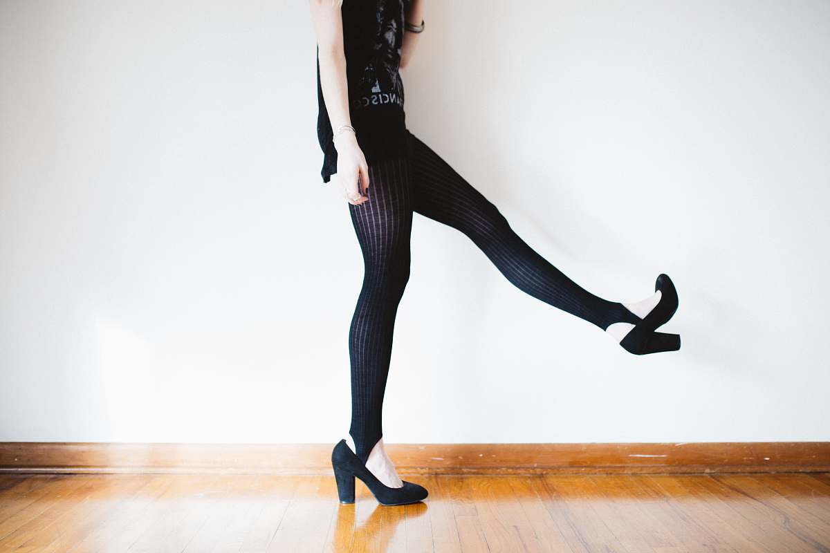 female woman raising her right leg near wall shoe