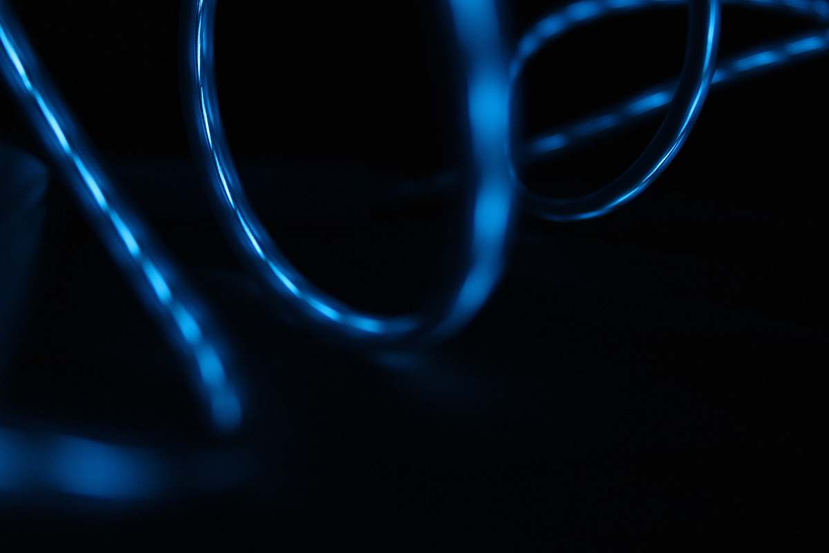 light Blue light reflected in the surface of glossy swirling wires dark