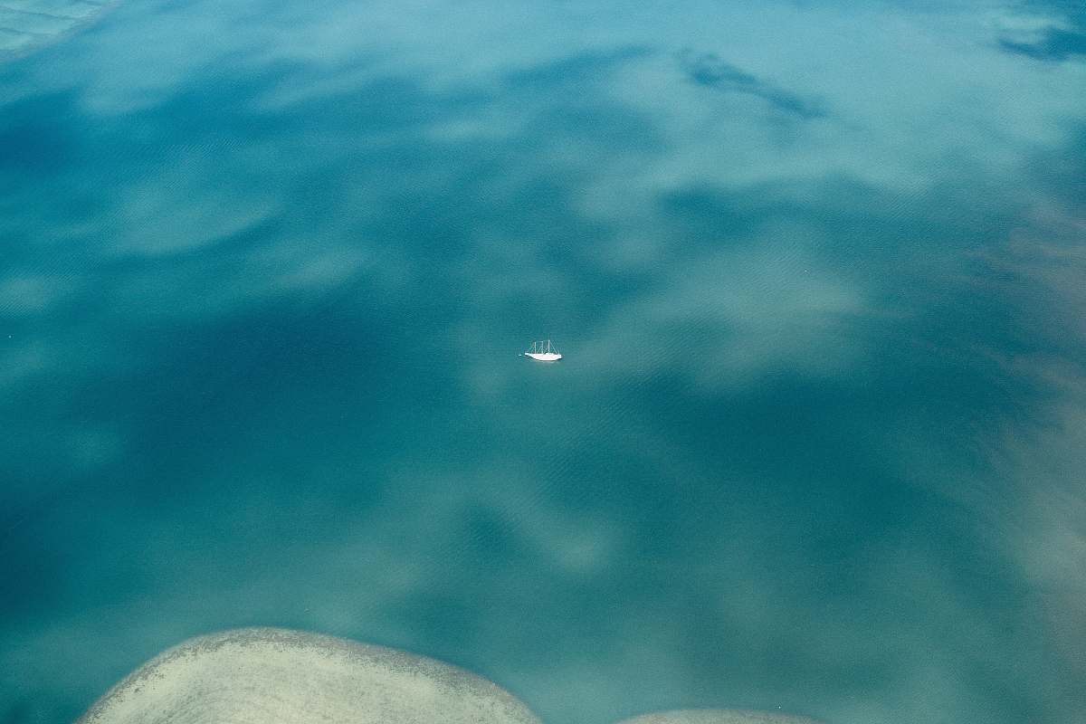 water blue sea with white boat sail