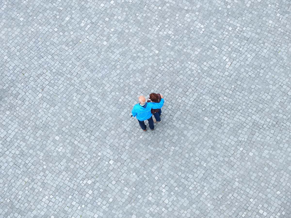 teal high-angle photo of man and woman standing in the middle of gray concrete paving grey