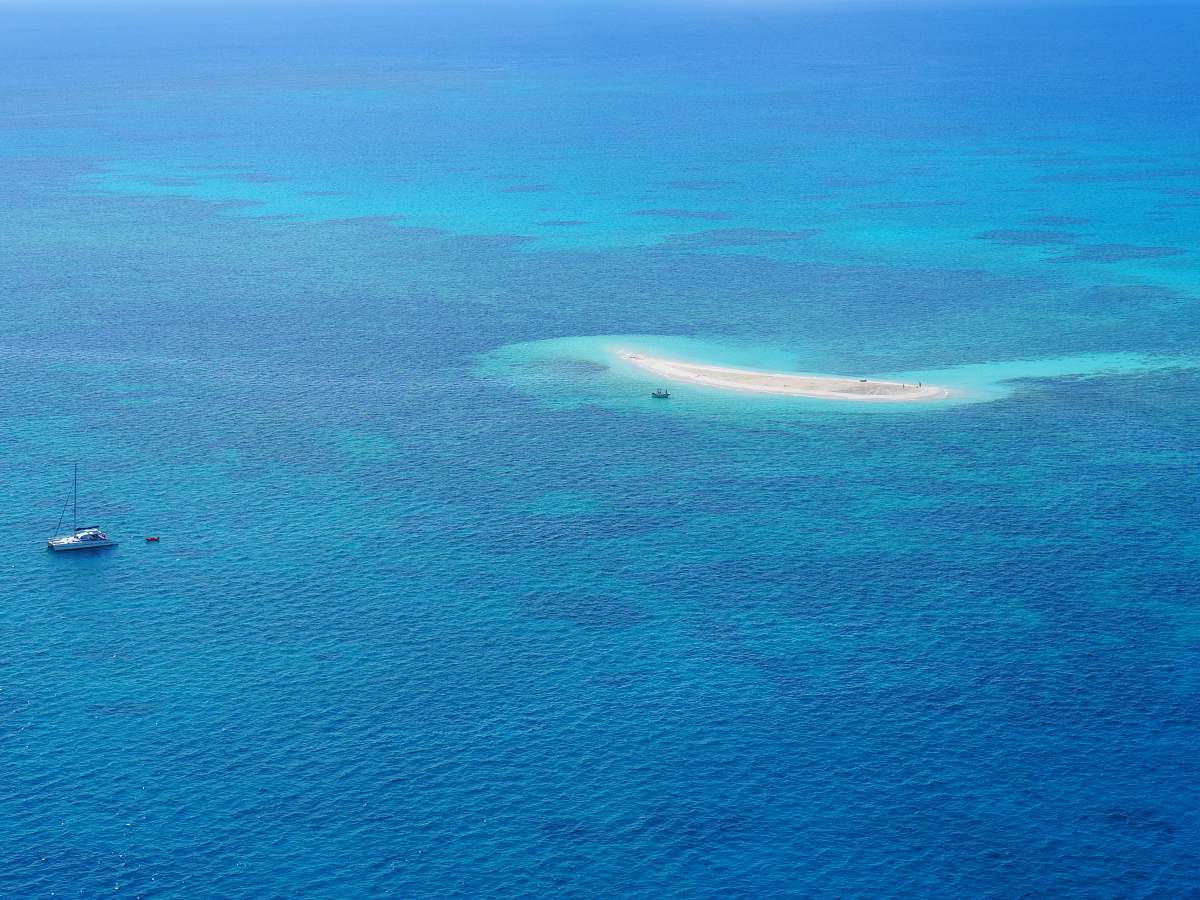 sea high-angle photography of boat near island water