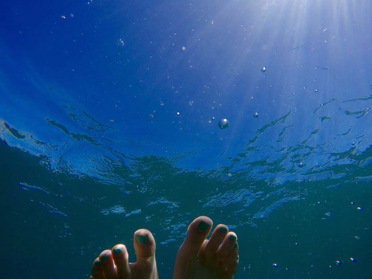 feet human feet on body of water during daytime underwater