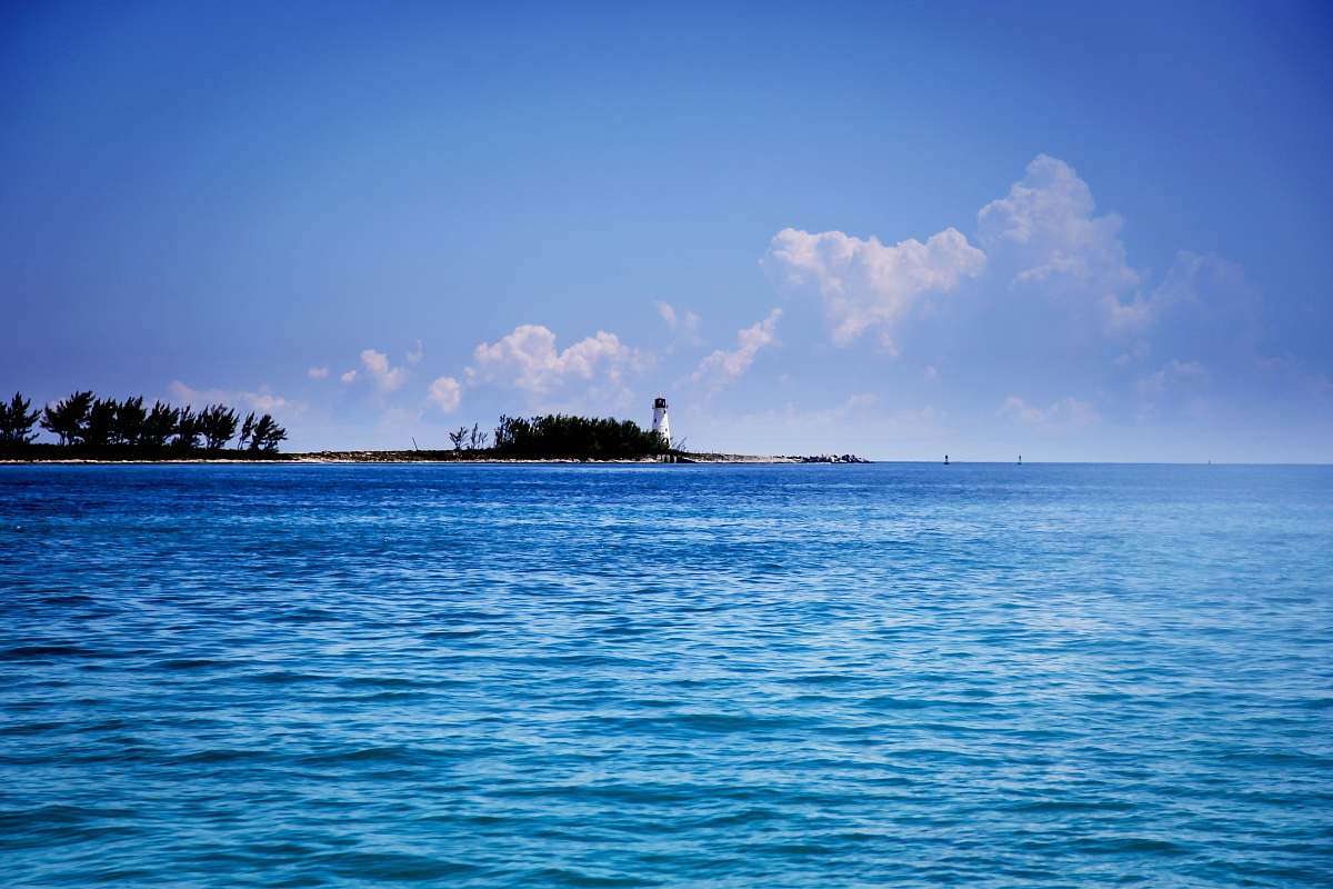 ocean lighthouse under cumulus clouds water