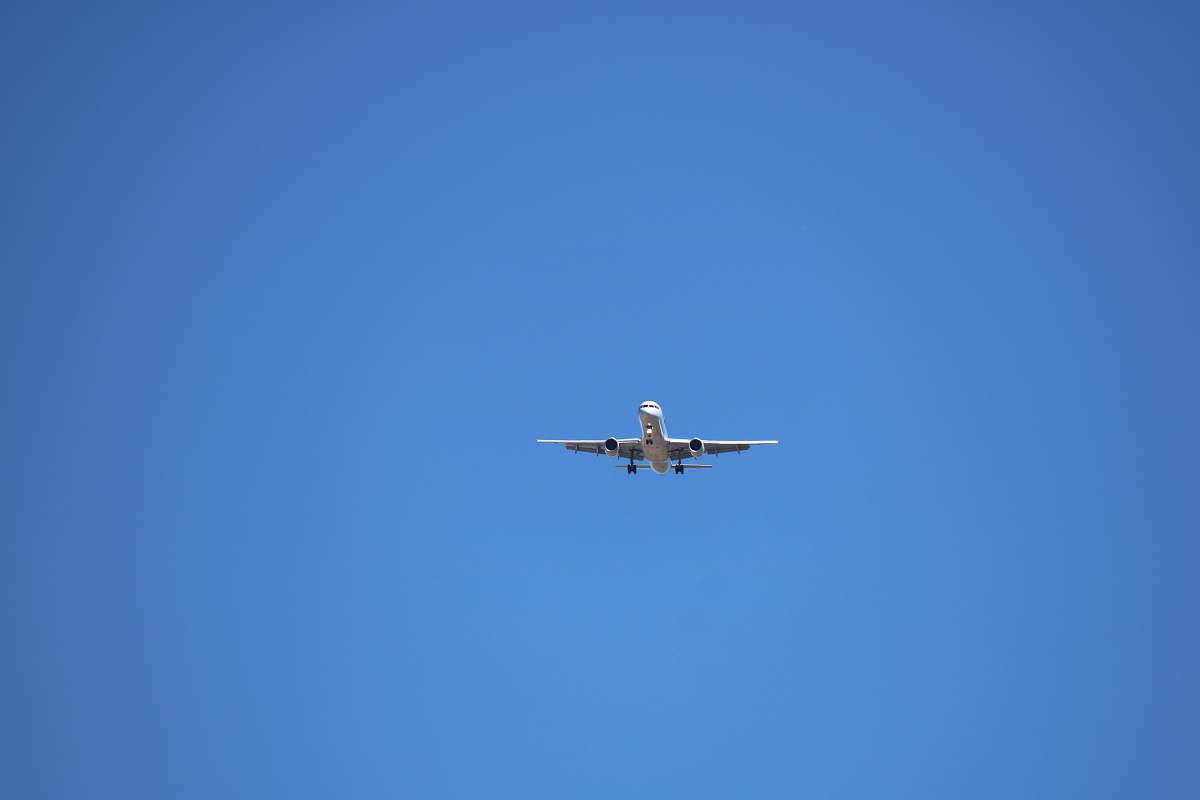 aircraft low angle photography of gray airplane under blue sky at daytime airplane