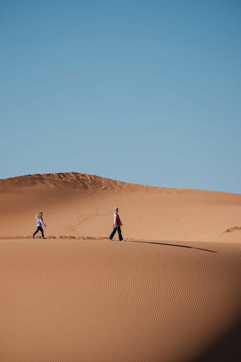 desert man and woman walking on brown sands dune