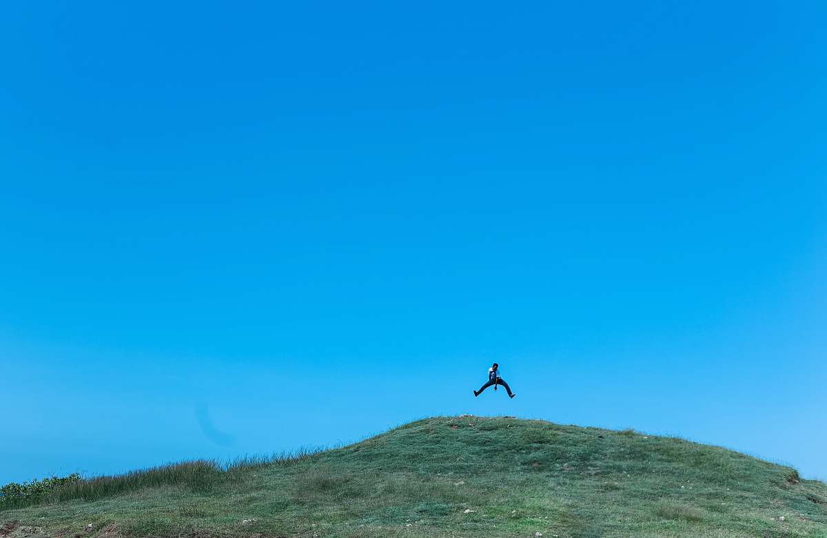 nature man jumping on cliff at daytime hill