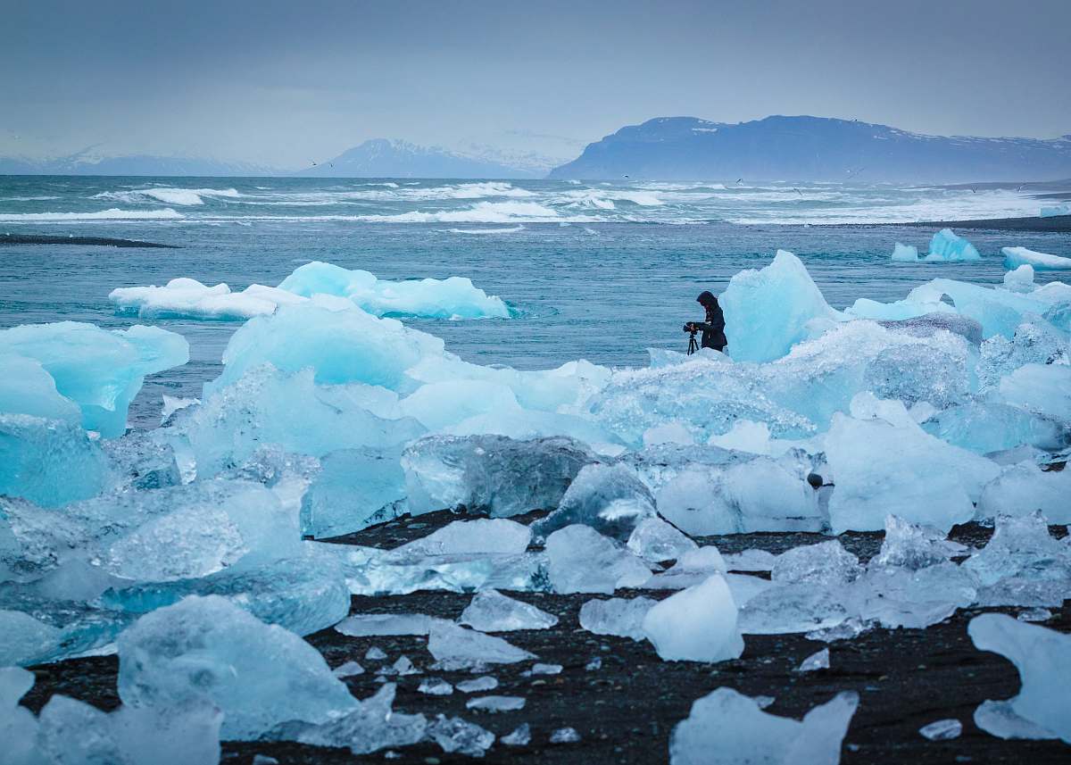 glacier man standing in middle of ice burg ice