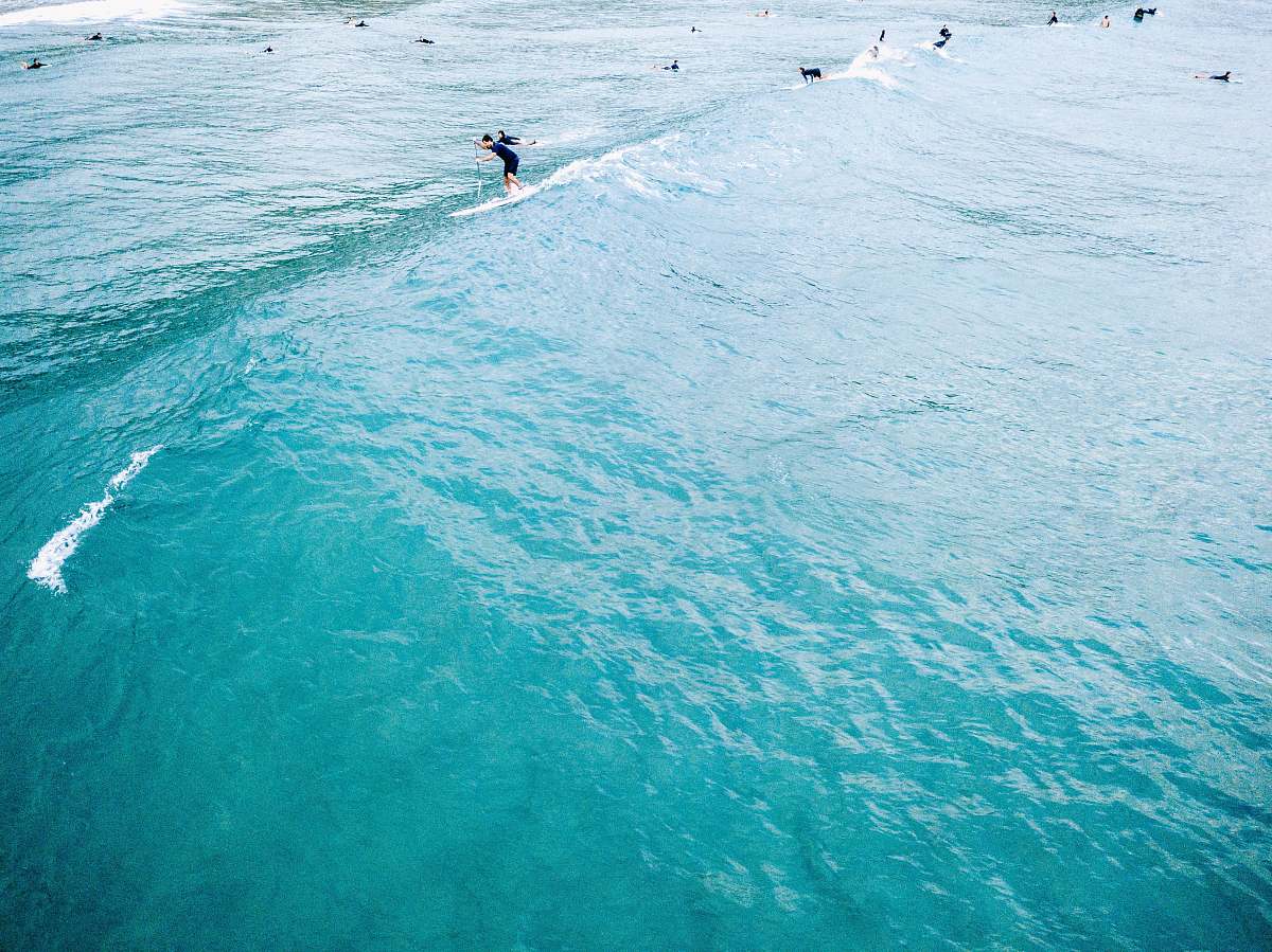 beach man standing on paddleboat surfer