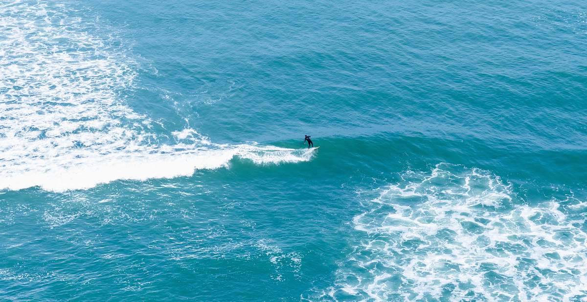ocean man surfing on body of water during daytime surfing