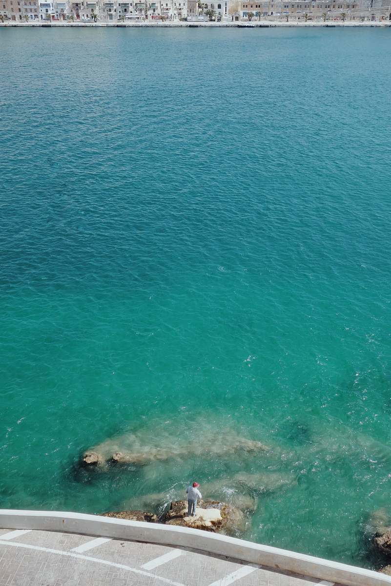 malta person standing on rock beside body of water sea