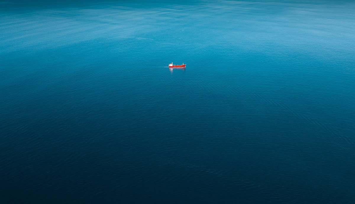 ocean red ship sailing on body of water alone sea