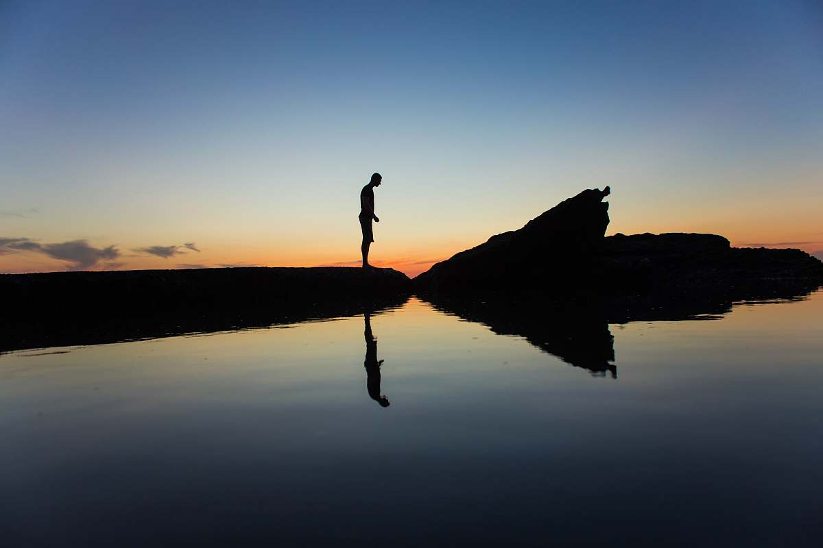 nature silhouette of man standing on land near body of water with reflection laguna beach