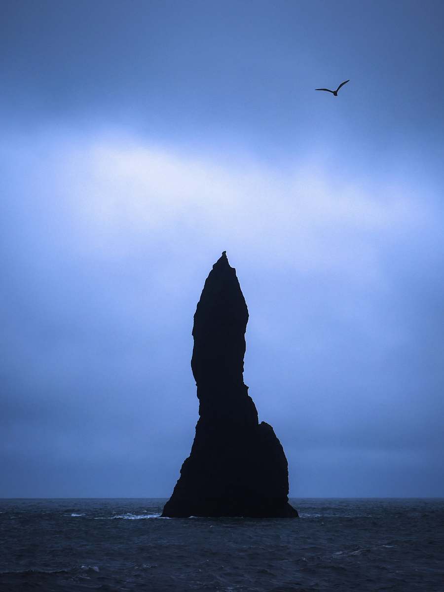 iceland silhouette of rock formation in the middle of sea cliff