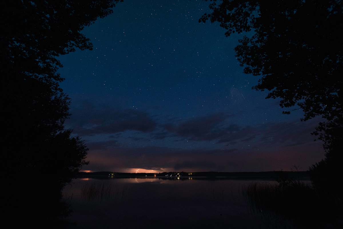 night silhouette of trees near body of water at nighttime thunder lake