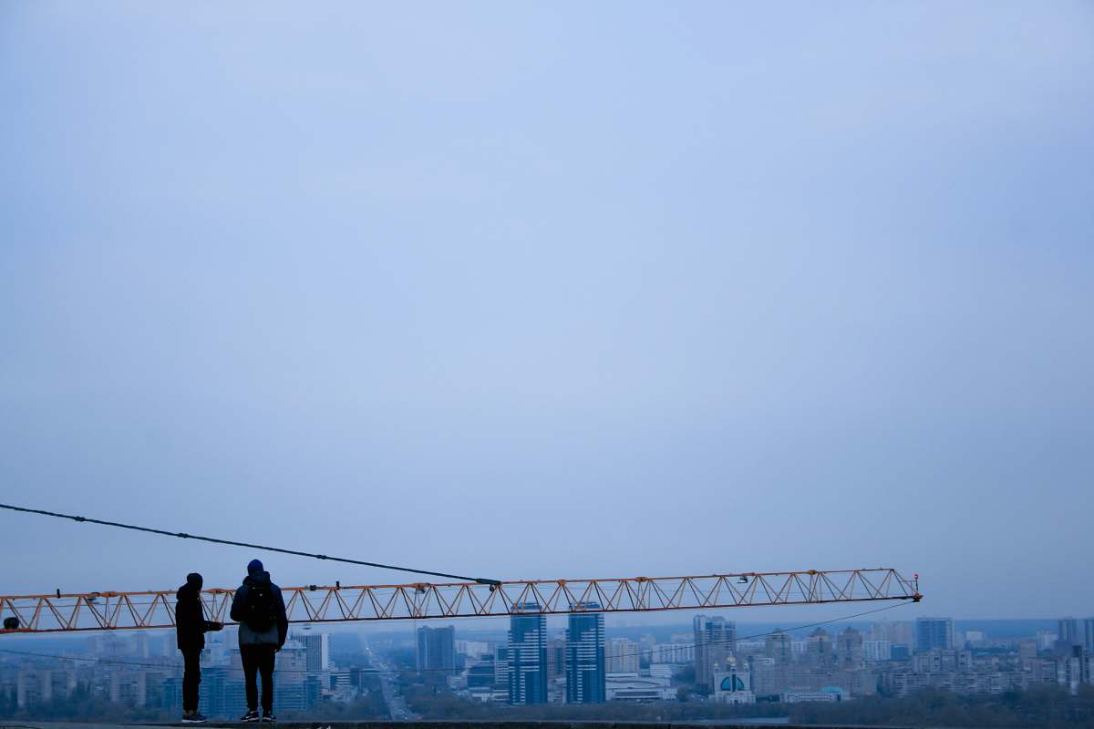 human silhouette of two person in front of yellow crane person