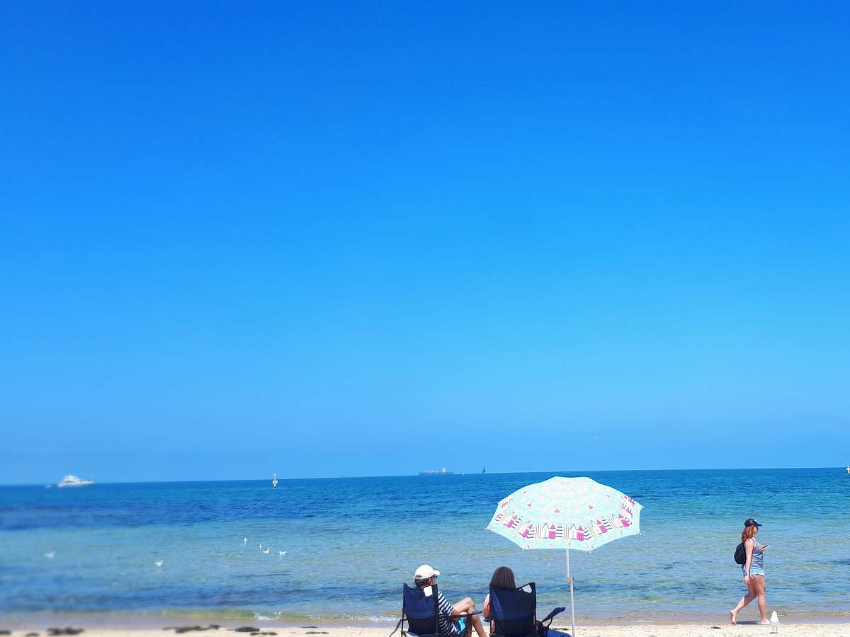 human two women sitting by the seashore during daytime person