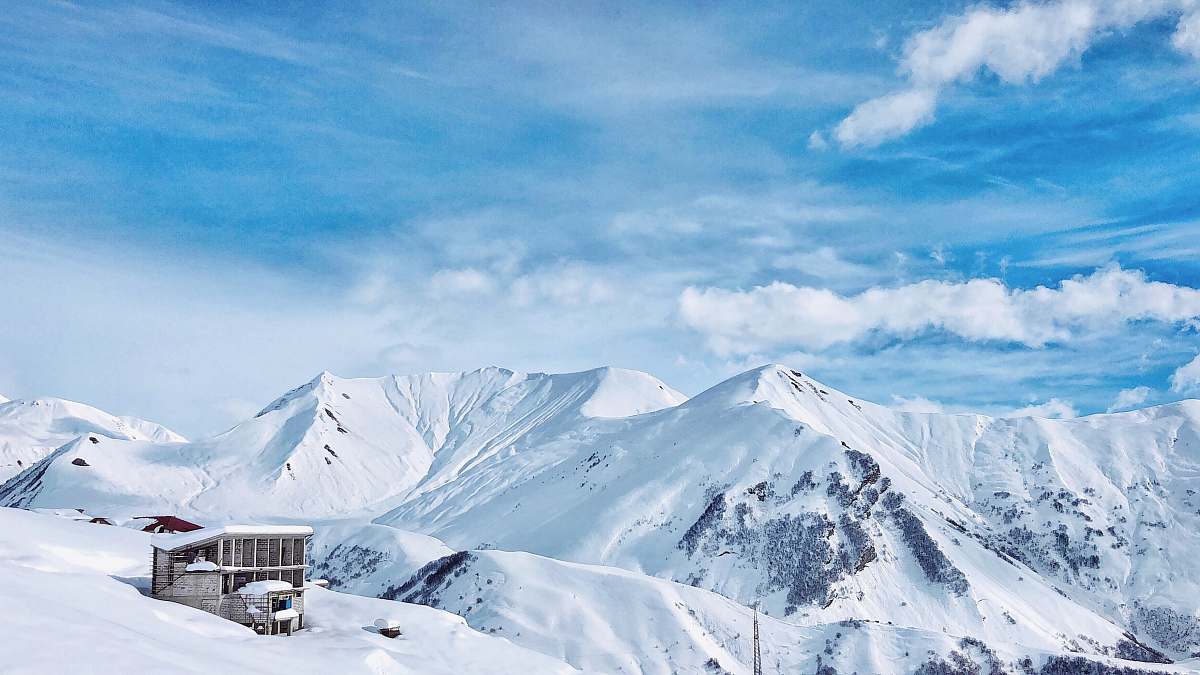 outdoors brown house in the middle of snow field mountain