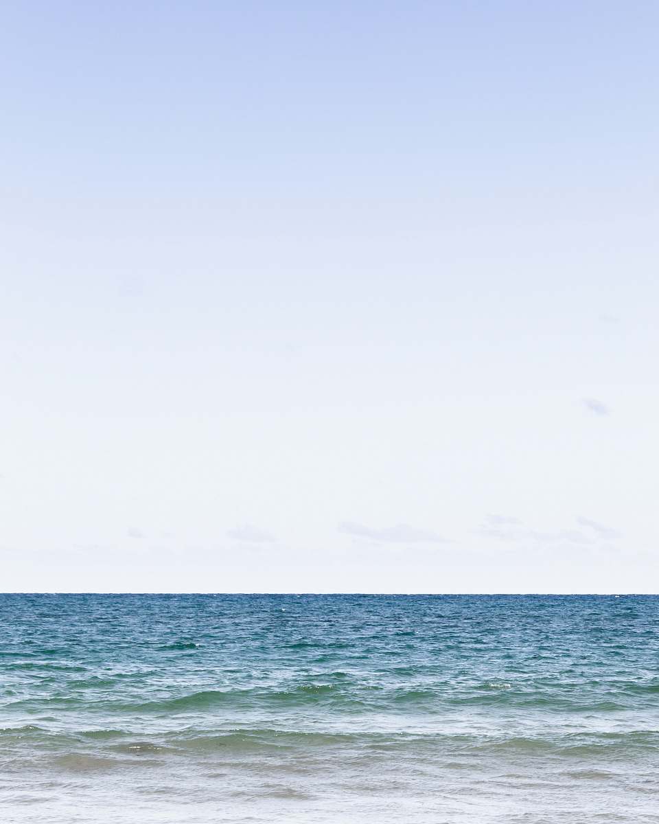 blue calm sea under clear blue sky during daytime ocean