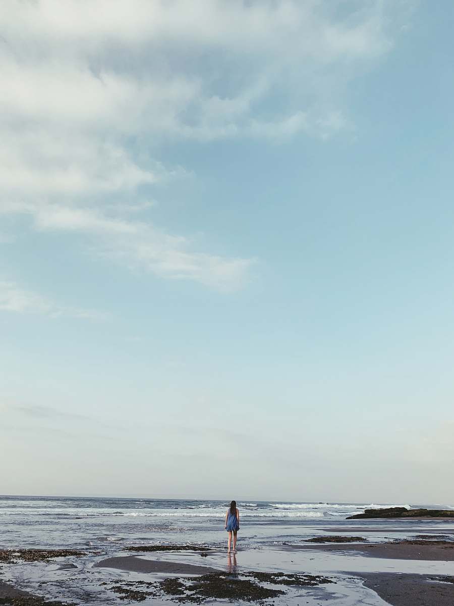 blue landscape photo of a woman on a beach outdoors
