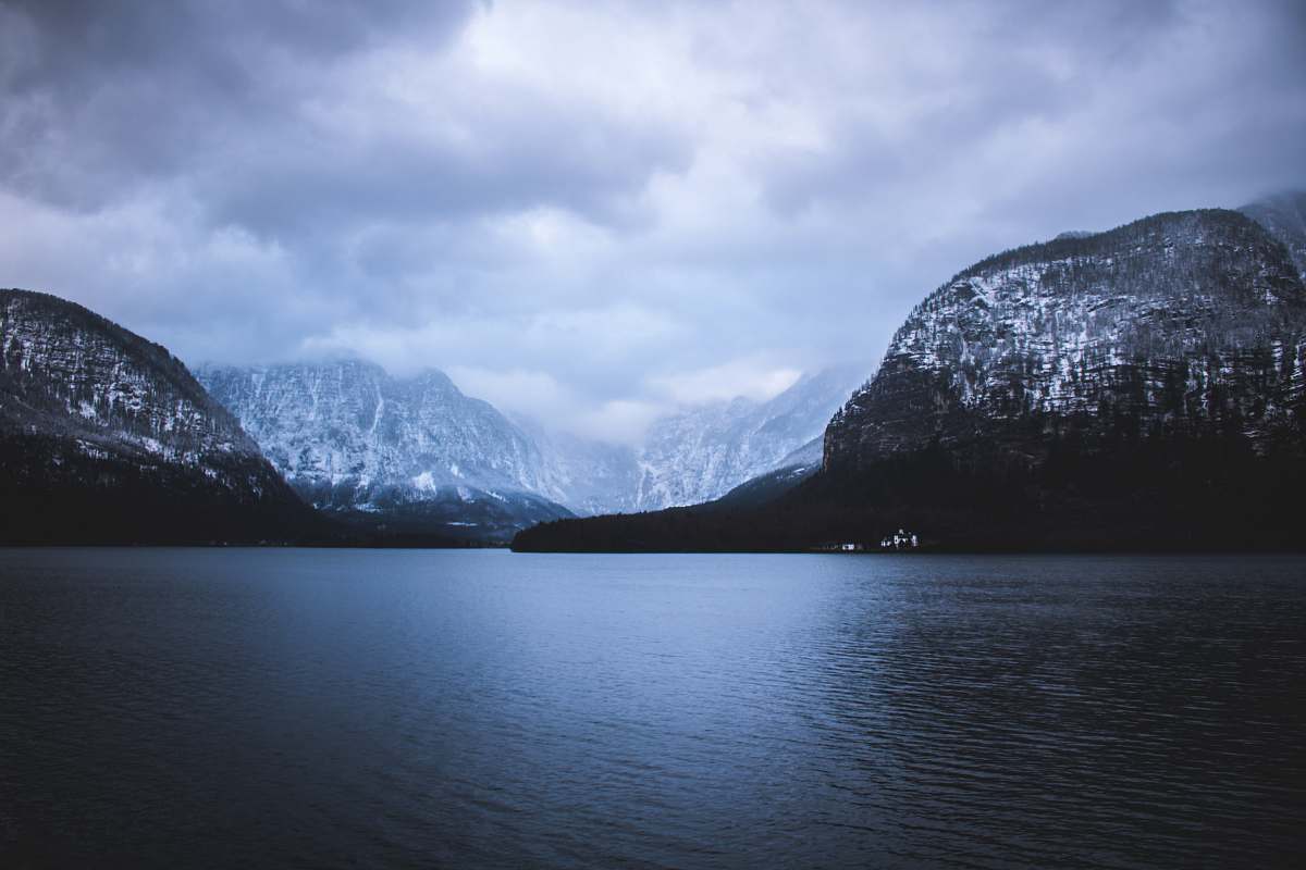 blue landscape photography of mountains near body of water under cloudy sky mountain