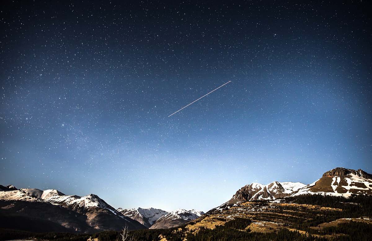 mountain photo of shooting star over snow covered mountains sky