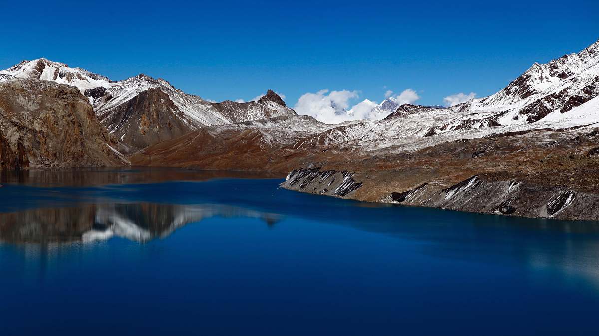 mountain snow coated mountain beside body of water snow