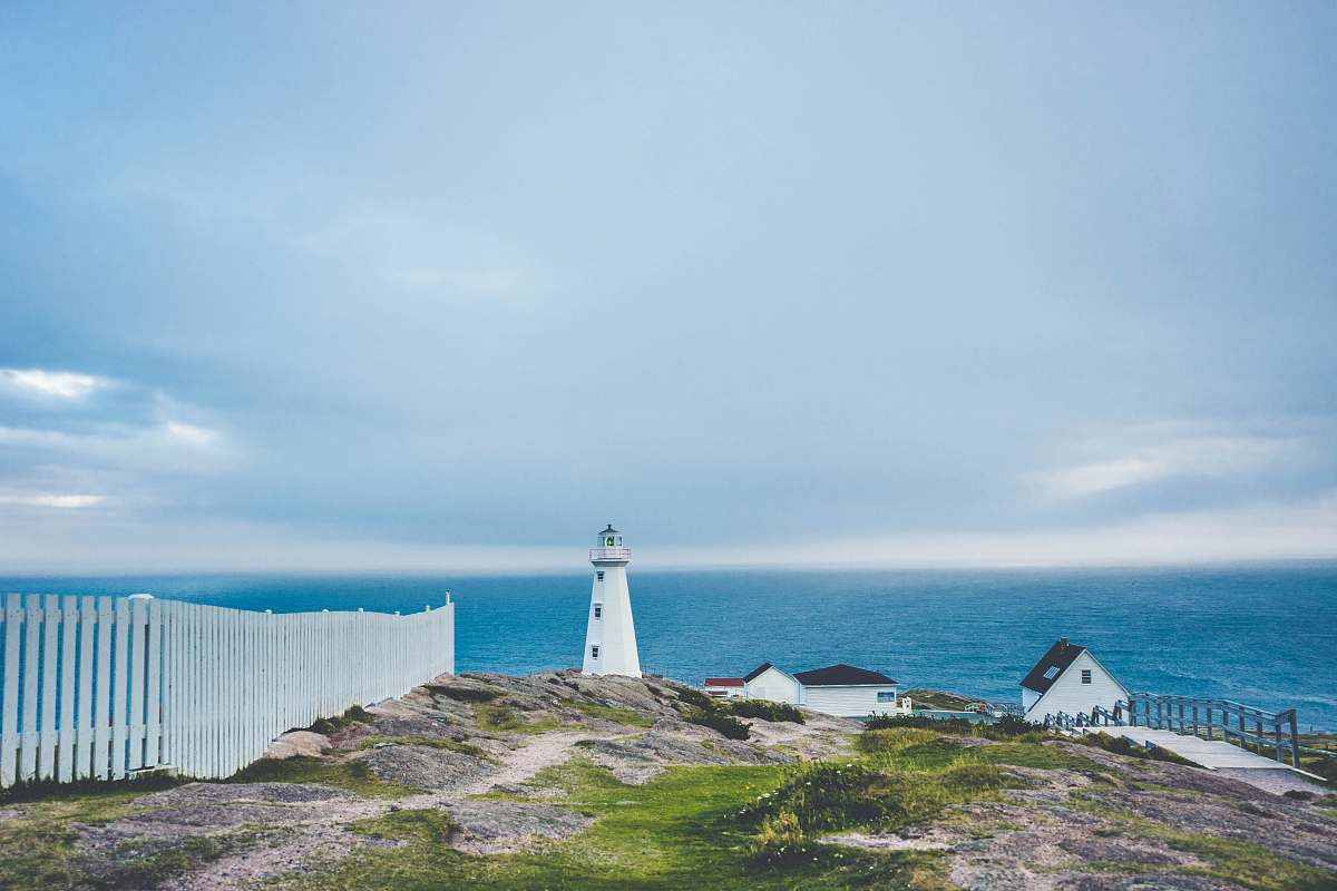 lighthouse lighthouse on cliff near fence and house coast