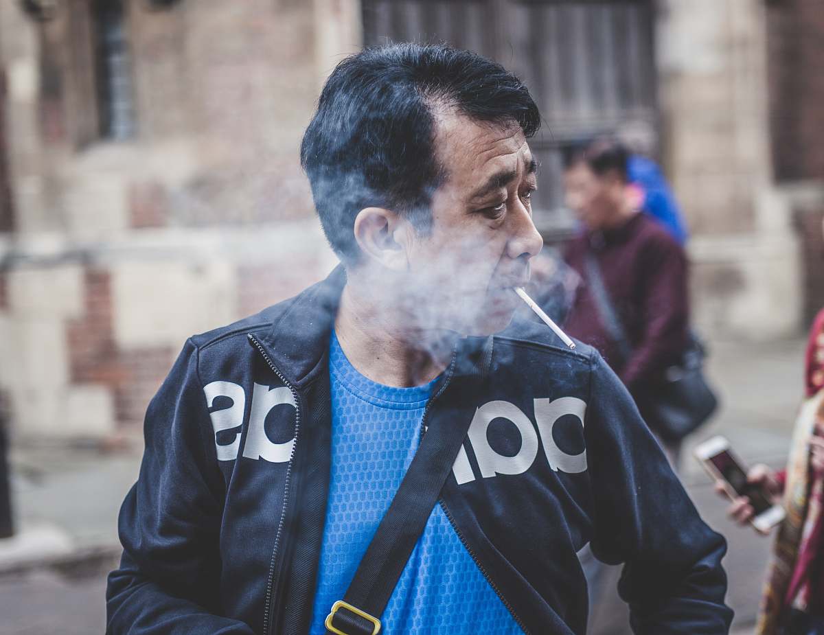 human man in black Adidas leather jacket smoking cigarette people